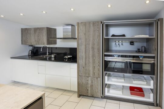 Witte keukenwand met zwart werkblad en grijze eiken kasten